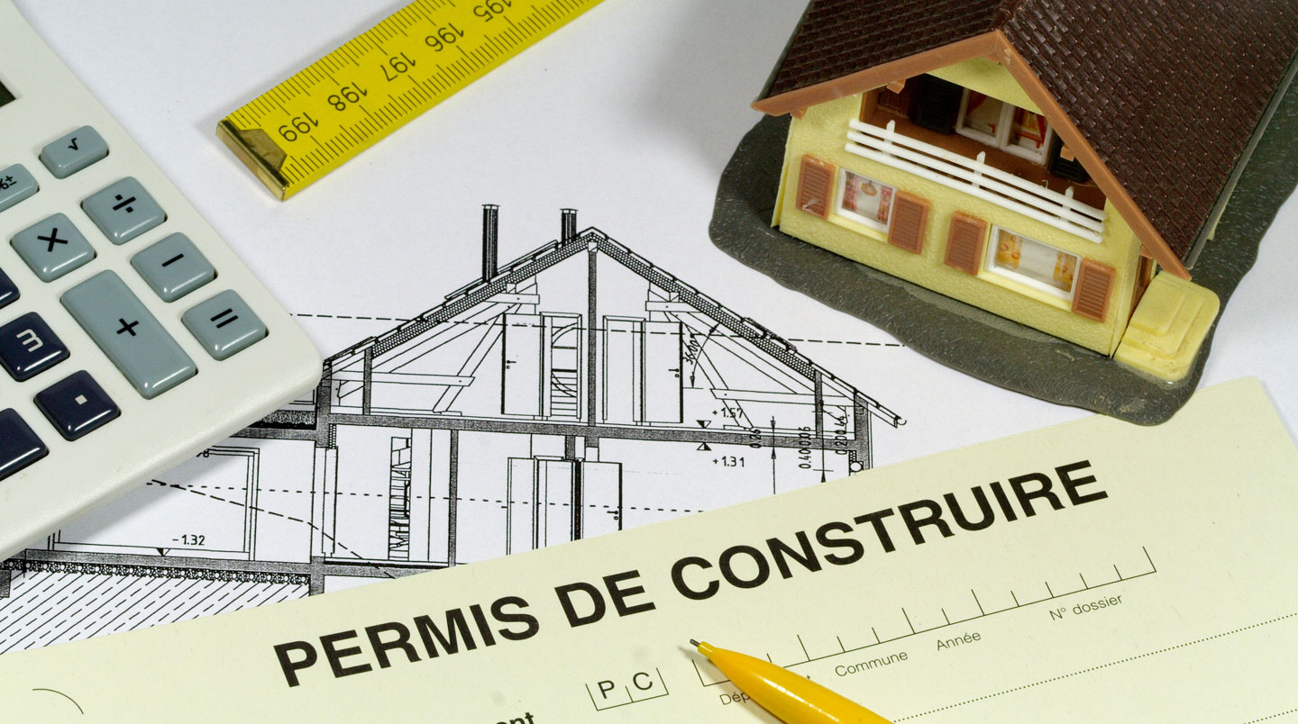 Panneau de permis d'urbanisme belge en français devant un chantier de construction avec structure de bâtiment en arrière-plan